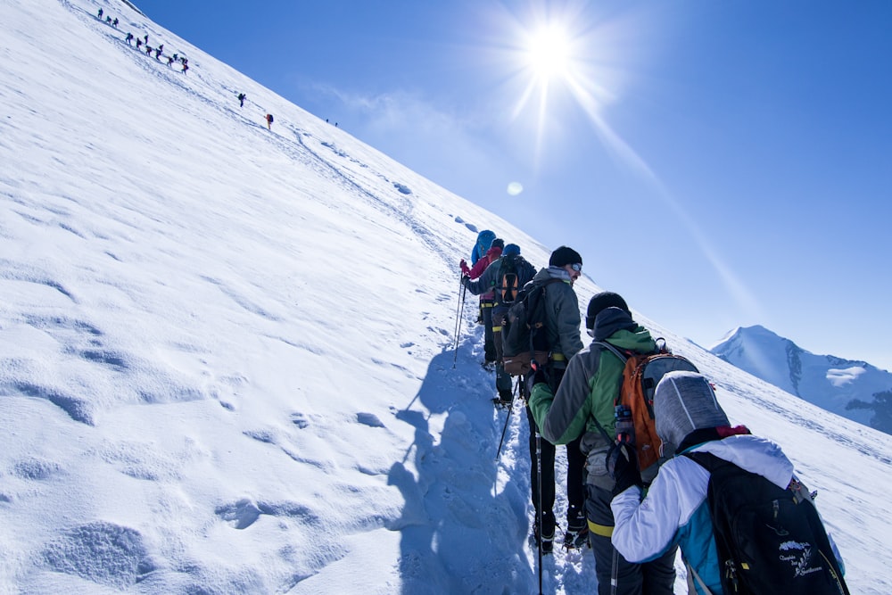 people hiking on snow covered mountain during daytime