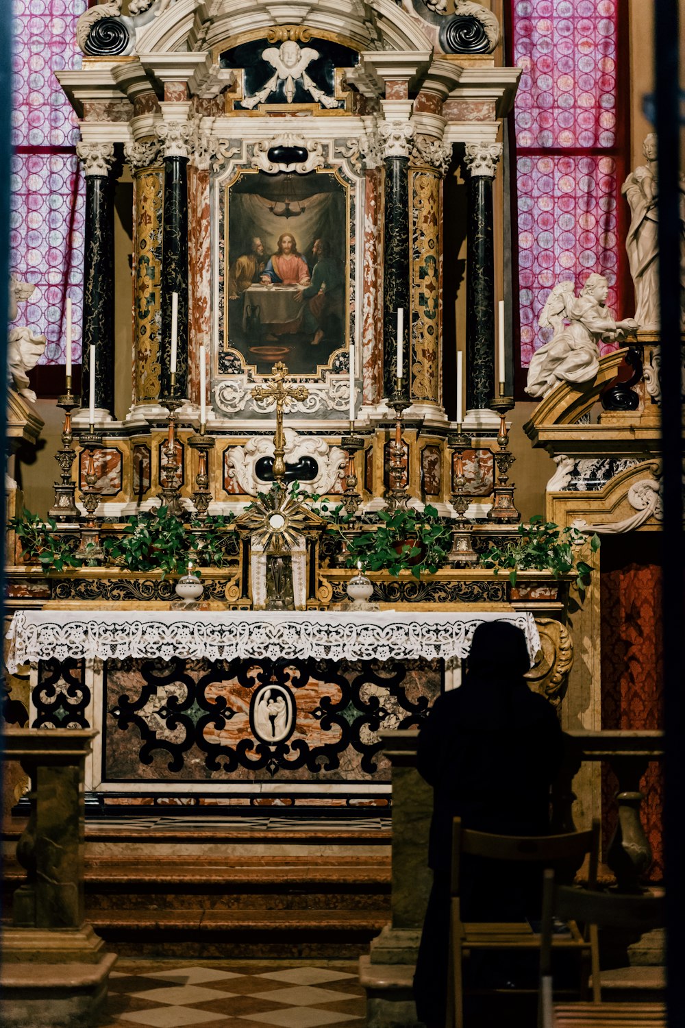 person in black robe standing in front of gold and black cathedral