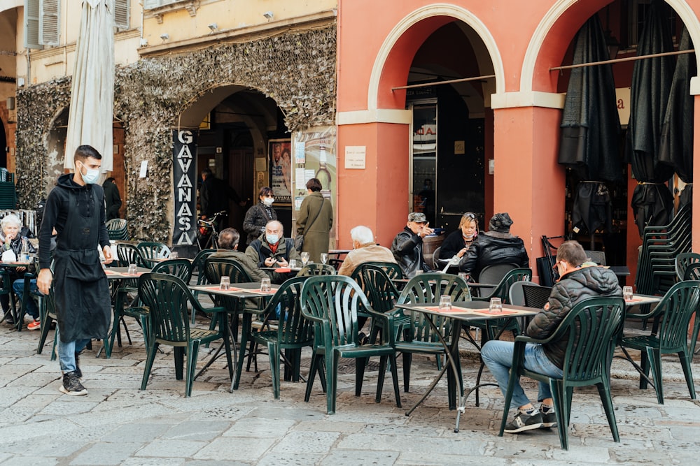 people sitting on green chairs near brown concrete building during daytime