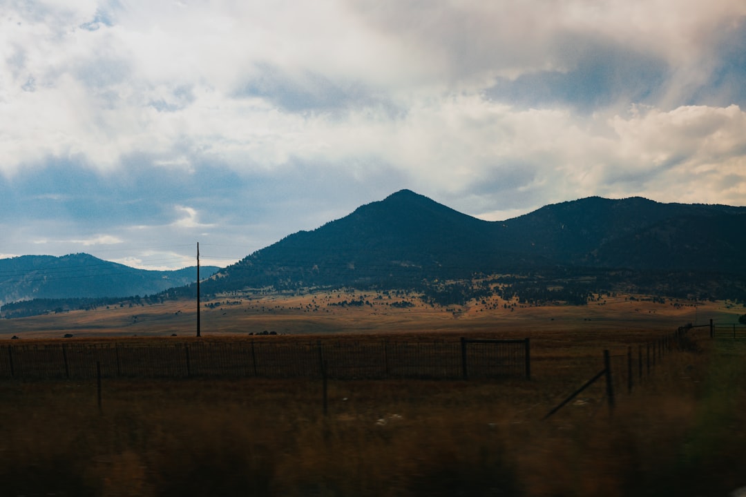 brown field near mountain under white clouds during daytime