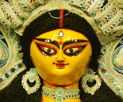 Close-up of a beautifully dressed Oxum figure in traditional attire with golden accessories.