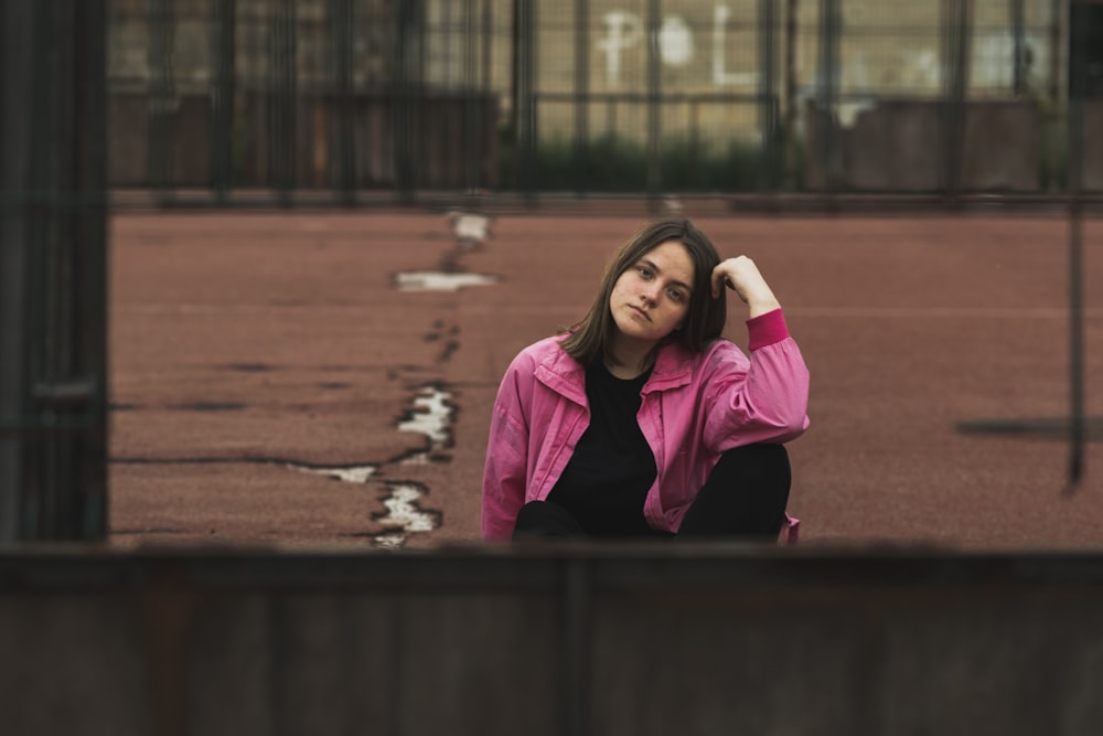 a woman in a pink jacket sitting on the ground