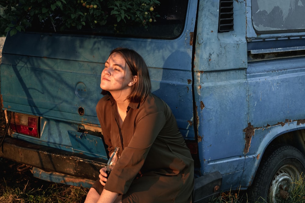 a woman sitting on the ground next to a blue van