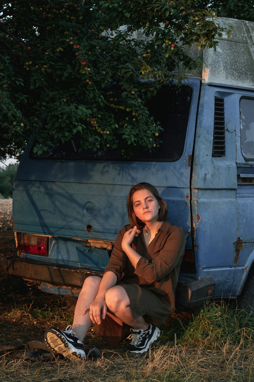 a woman sitting on the ground next to a van