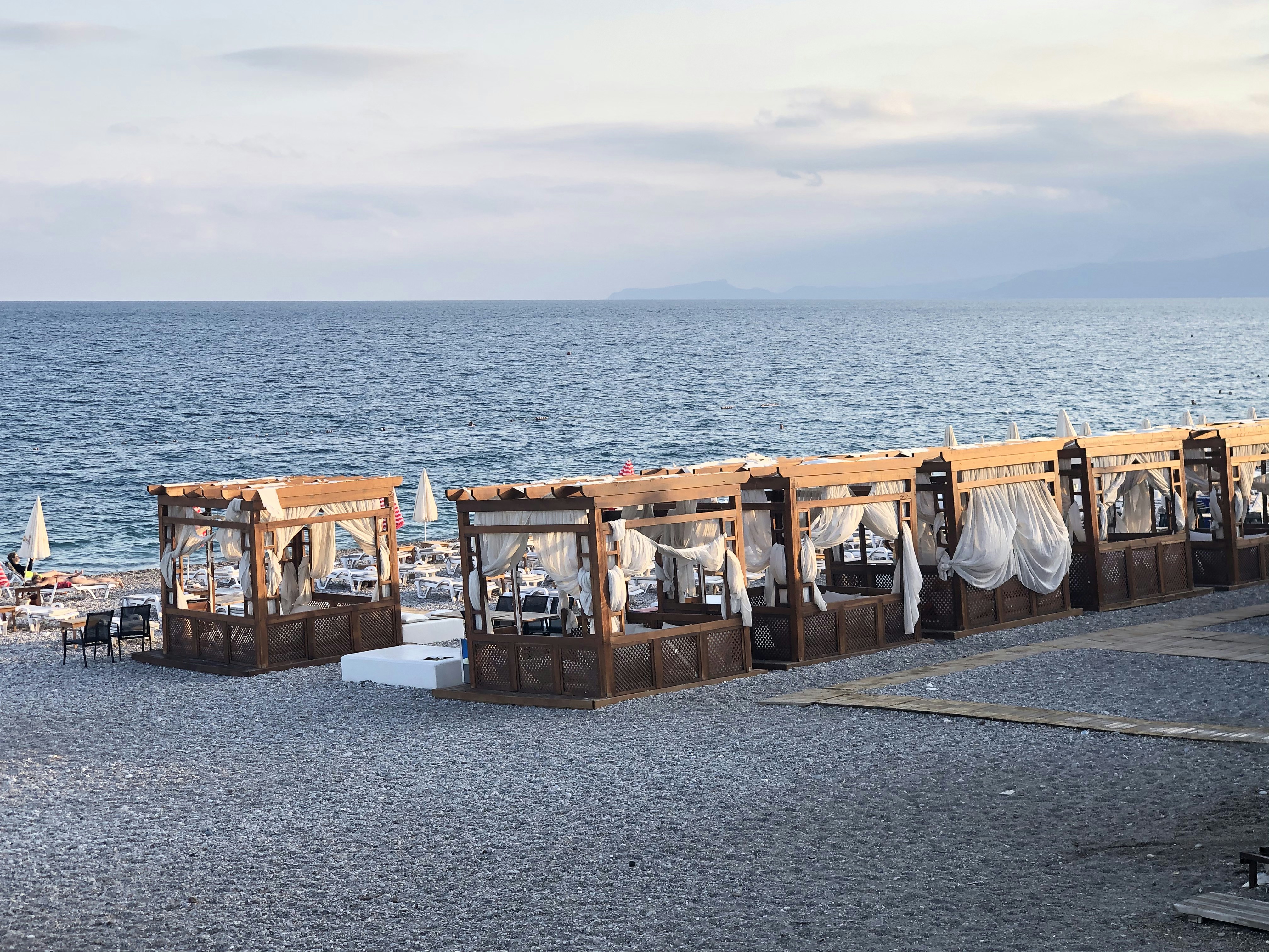 brown wooden crates on gray concrete floor near body of water during daytime