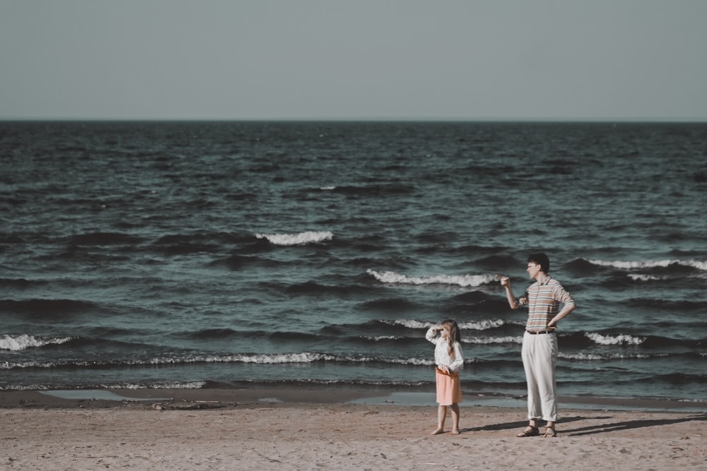 man and woman standing on beach during daytime