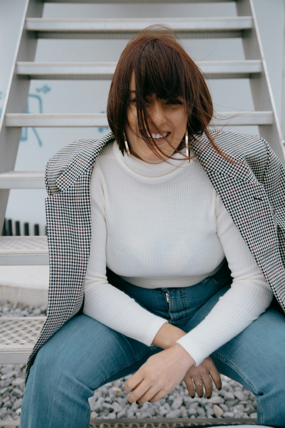 woman in white turtleneck sweater and blue denim jeans sitting on white wooden staircase