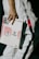 A person wearing a white outfit with black stripes is holding a GQ magazine featuring Tyler, The Creator. The magazine cover is predominantly white with pink circular graphics.
