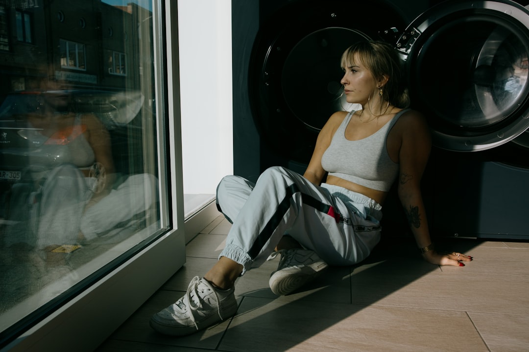 woman in white tank top and gray pants sitting on floor