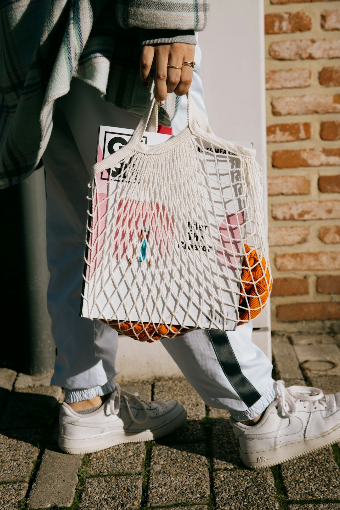 person holding white and red plaid tote bag