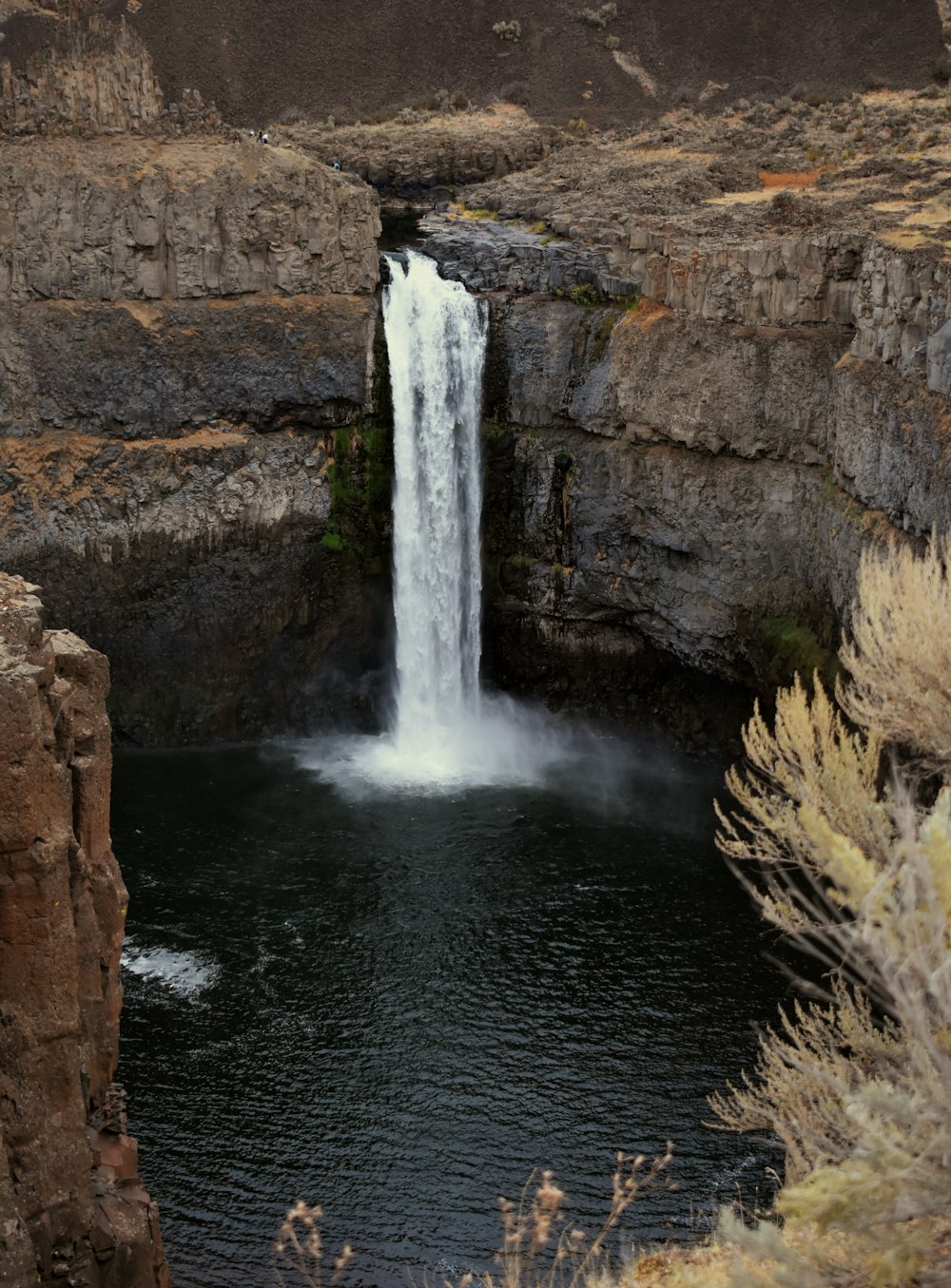 waterfalls between brown rocky mountain during daytime