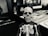 A small skeleton figurine is positioned in the foreground, with a skeletal body suit and a detailed skull. The background displays various game boxes and blurry, indistinct images, contributing to a mysterious and eerie atmosphere.