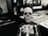 A small skeleton figurine is positioned in the foreground, with a skeletal body suit and a detailed skull. The background displays various game boxes and blurry, indistinct images, contributing to a mysterious and eerie atmosphere.