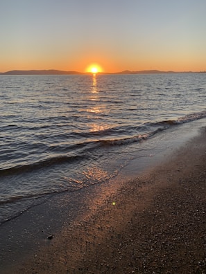 Sunset casting golden light over the calm waters of Samaná Bay with distant whale tails visible.