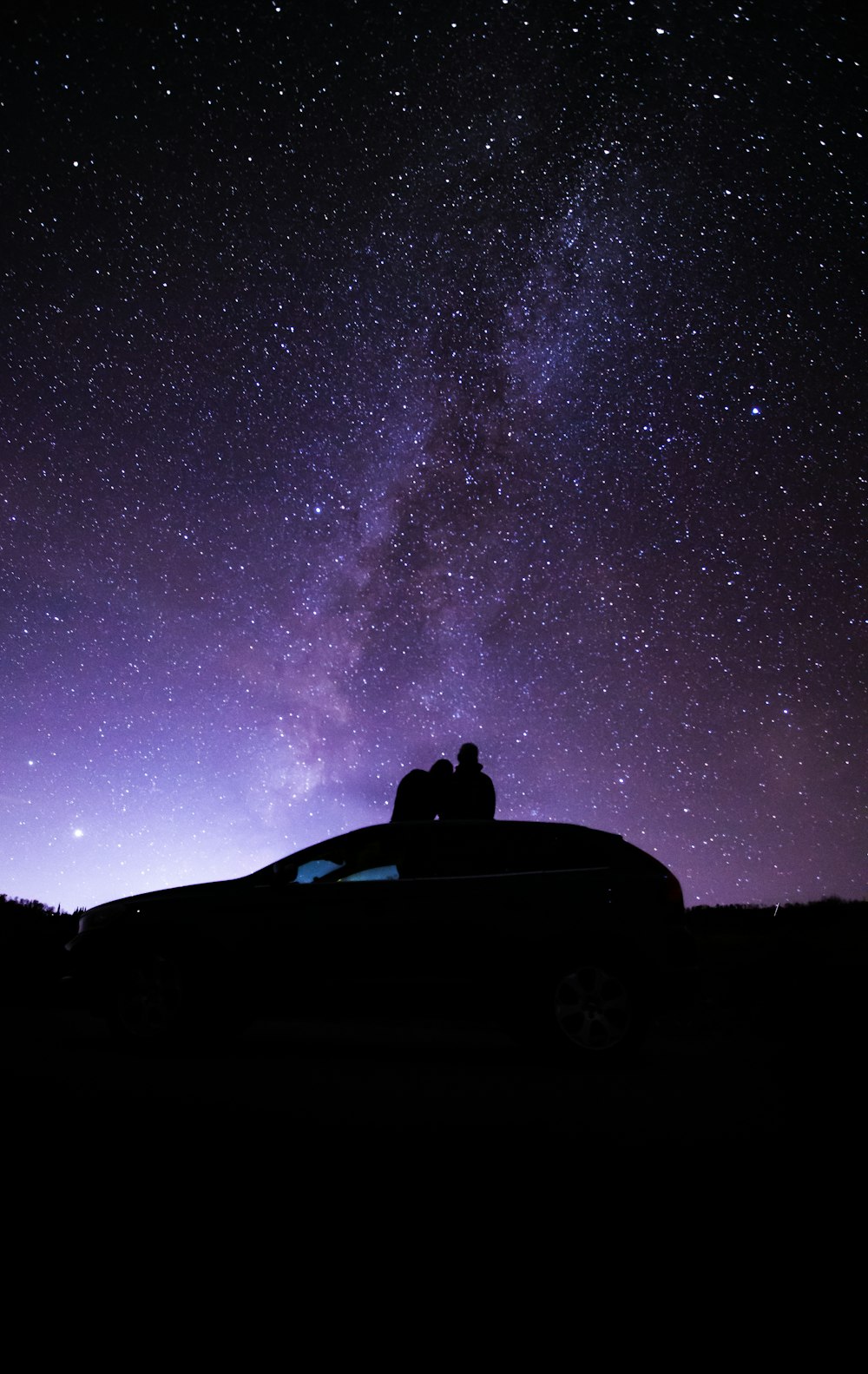 星空の下で車に座る人のシルエット