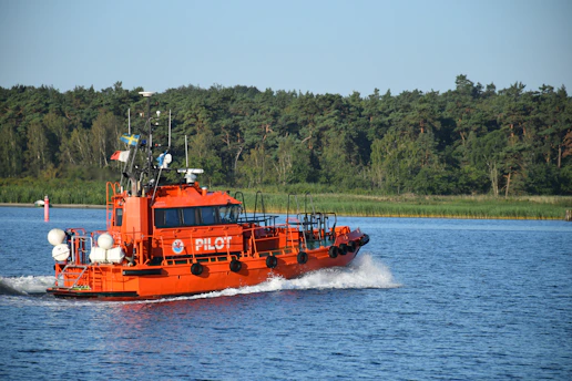 A pilot boat approaching a vessel with a marine pilot ready to board amid gentle waves.