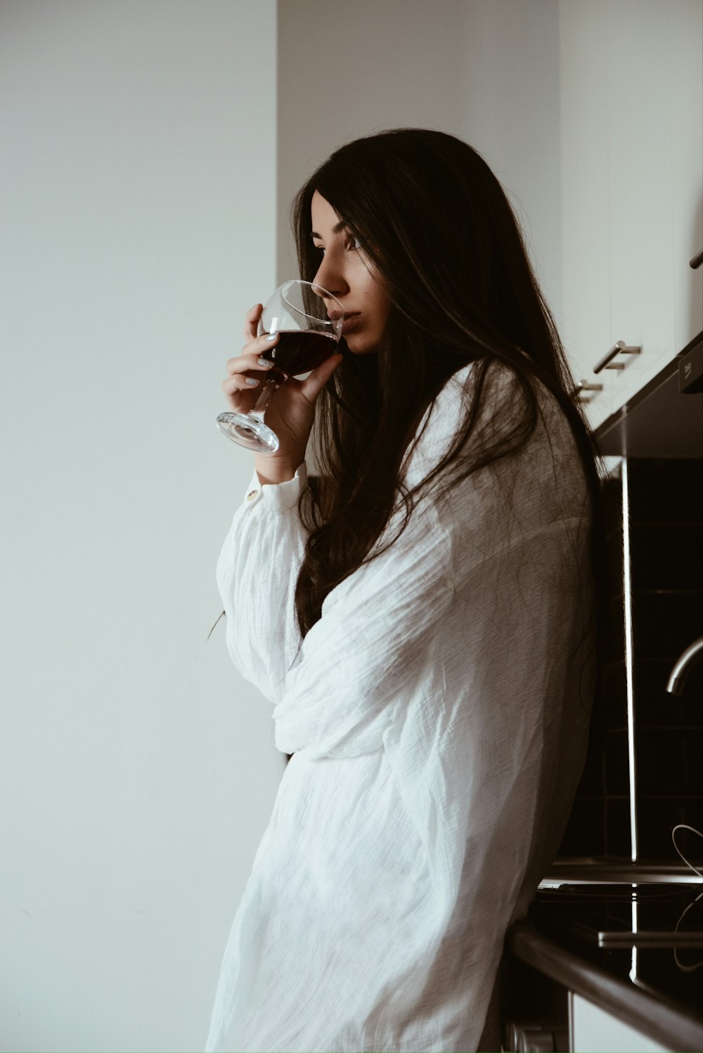 woman in white robe holding red ceramic mug