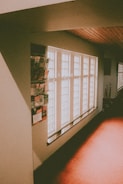 A hallway is illuminated with soft natural light streaming through several large, rectangular windows. The walls are adorned with various informational pamphlets and brochures. The flooring and ceiling feature a warm wooden tone, creating a cozy atmosphere.