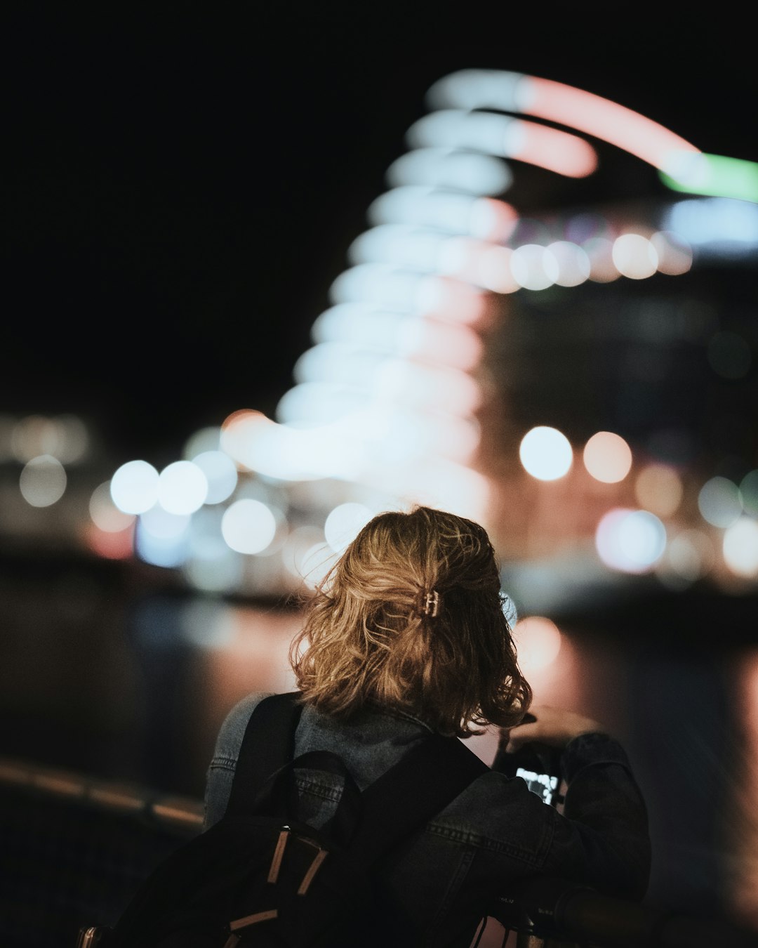 woman in black jacket standing on sidewalk during night time