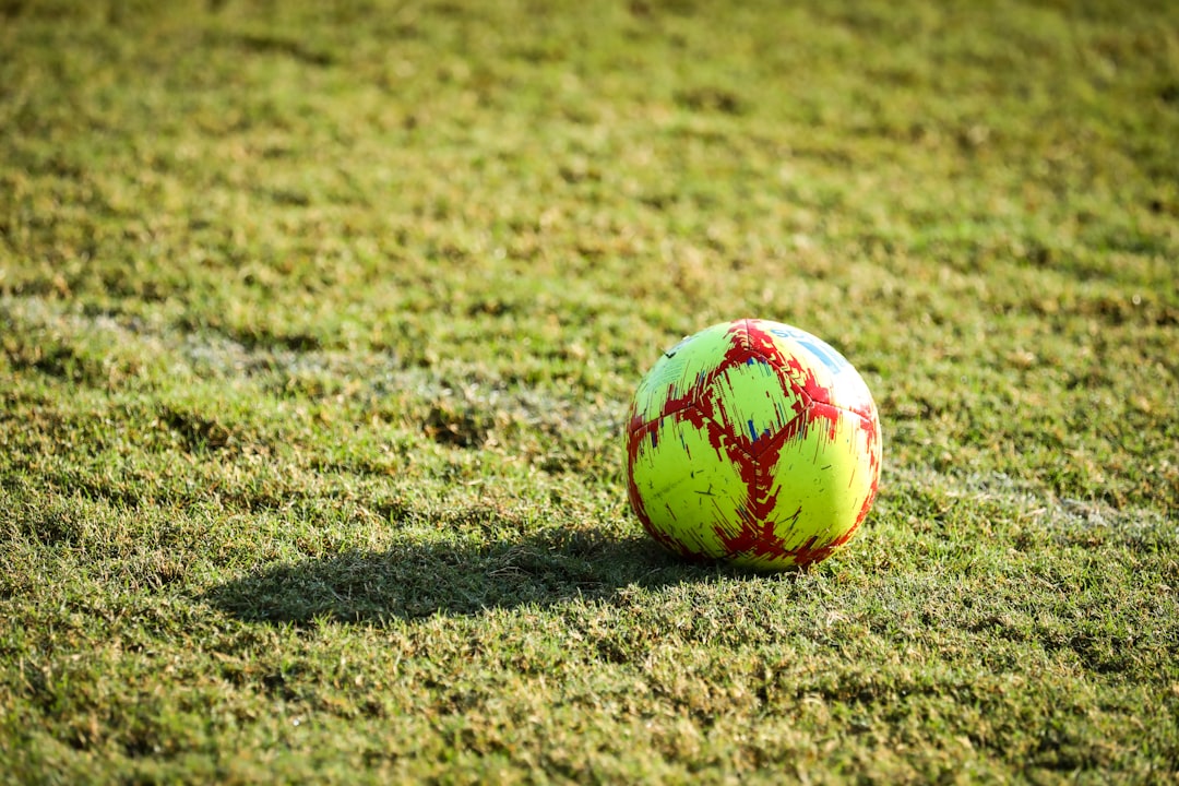 red and white soccer ball on green grass field during daytime