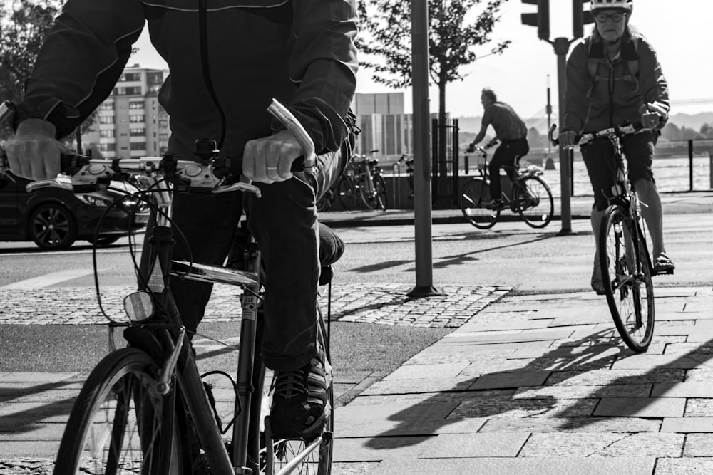 grayscale photo of man riding bicycle on sidewalk
