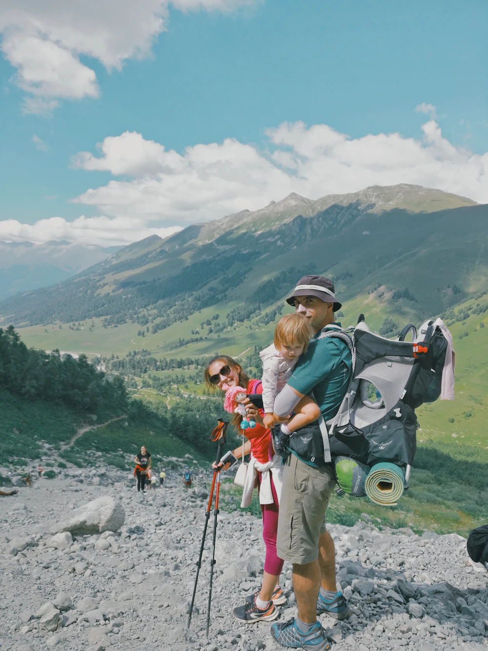 Two young hikers with backpacks climbing a rocky coastal trail