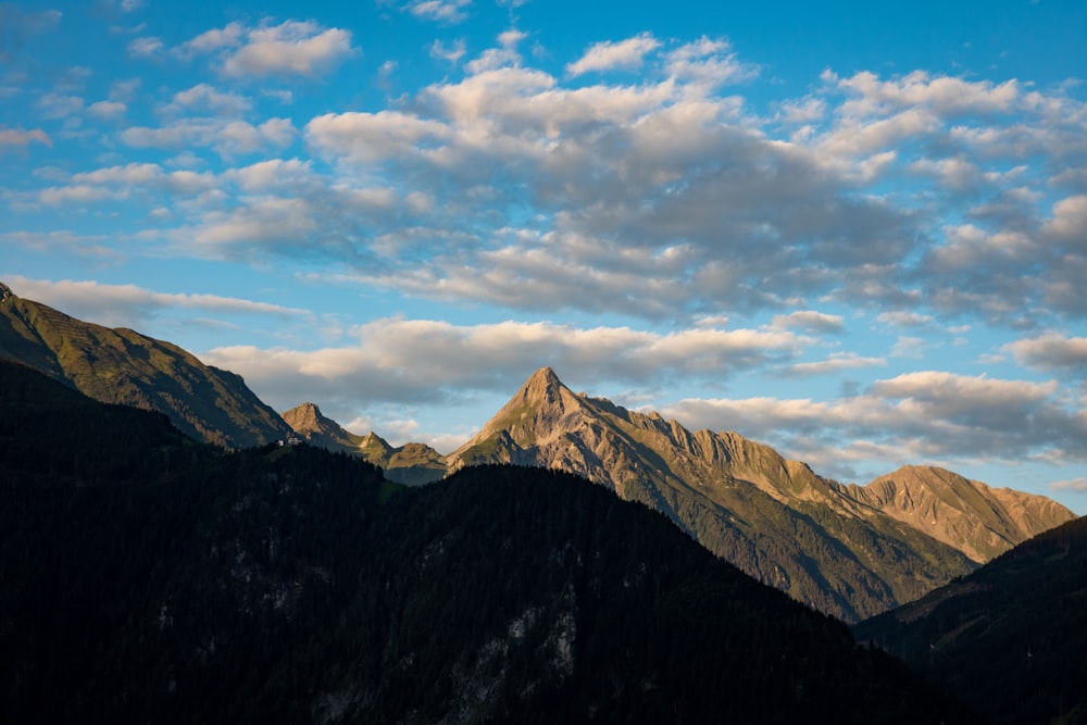 montagne marroni e bianche sotto nuvole bianche e cielo blu durante il giorno