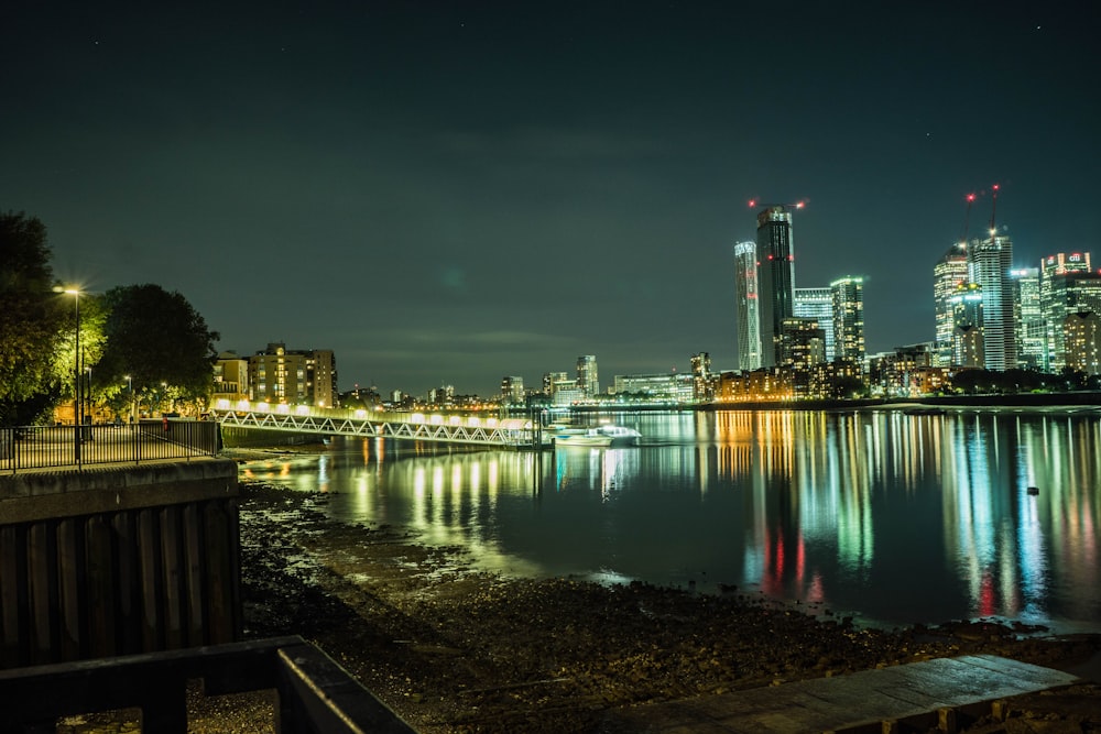 city skyline across body of water during night time