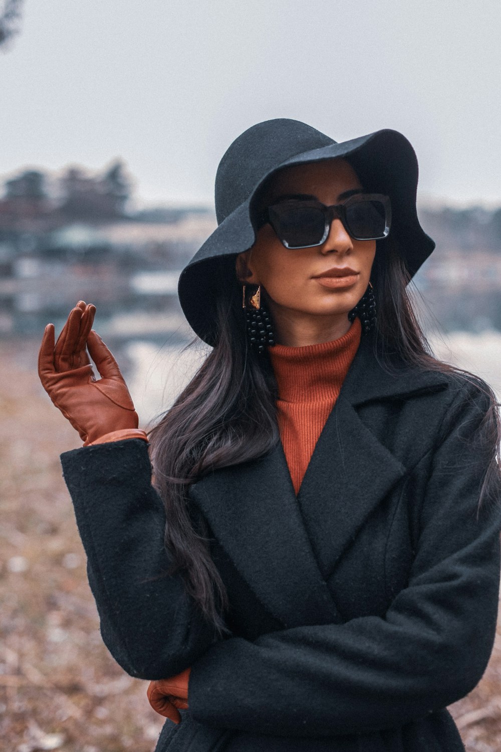 mulher no casaco preto vestindo óculos de sol pretos e chapéu preto