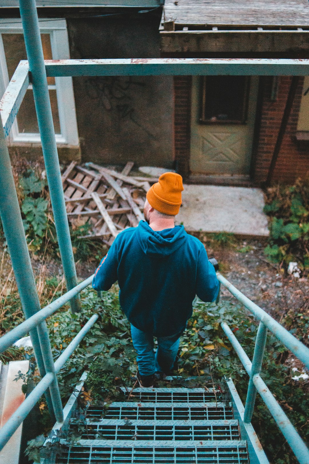 boy in blue jacket and yellow hat standing on a ladder