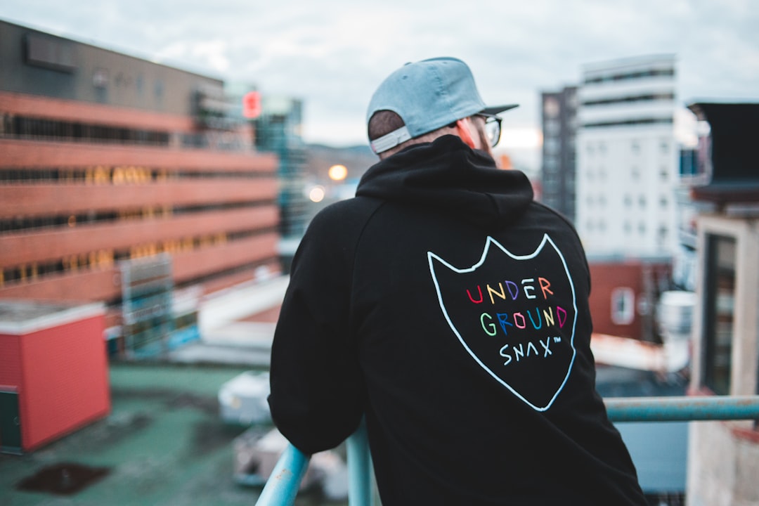 man in black hoodie wearing white baseball cap