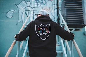 man in black hoodie standing on white metal ladder