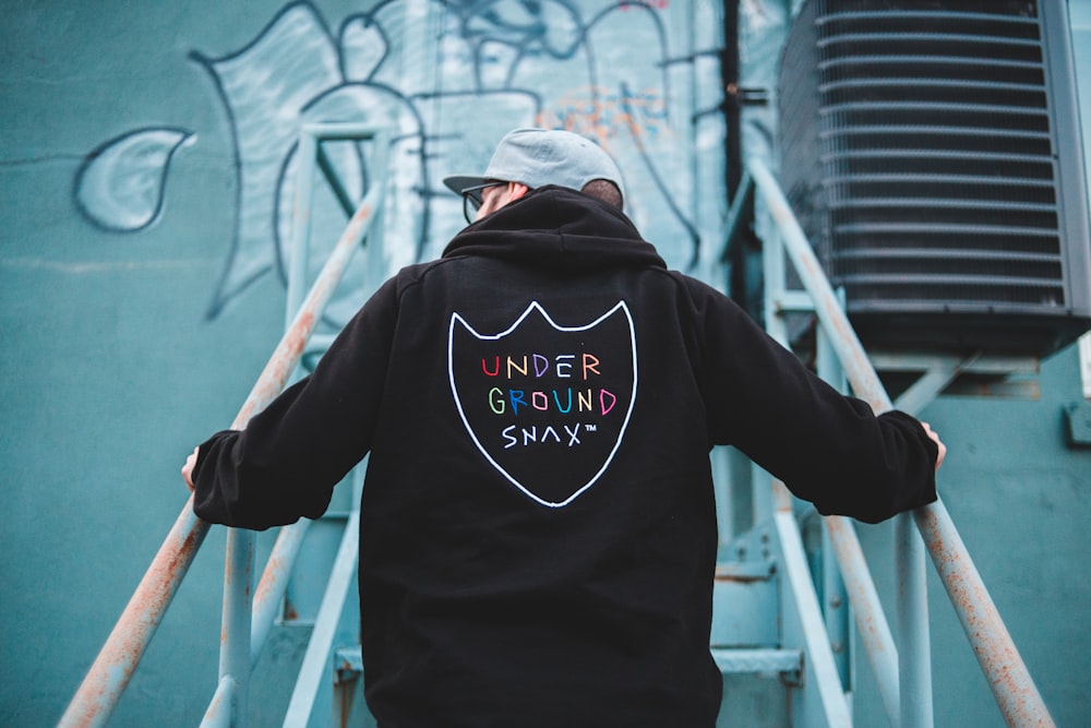 man in black hoodie standing on white metal ladder