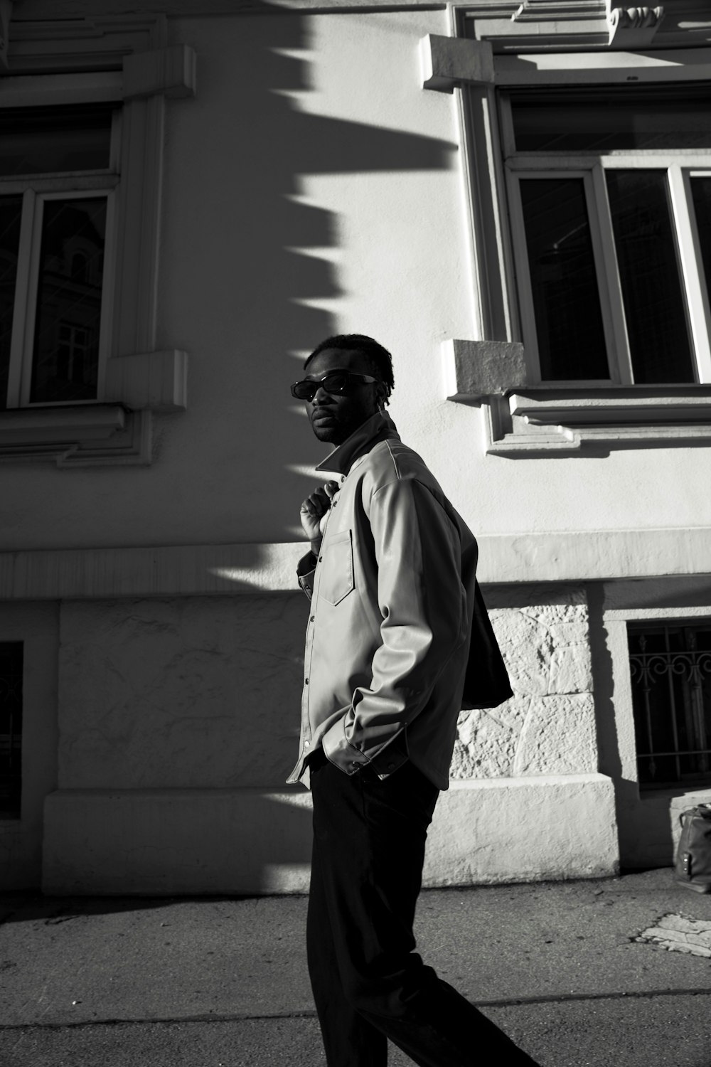 man in white dress shirt and black pants standing near window