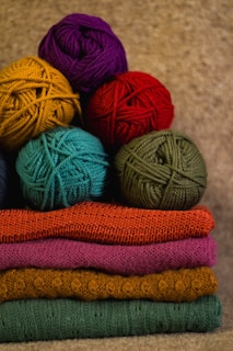 Cozy wool yarn balls and knitted sweaters arranged on a wooden table.
