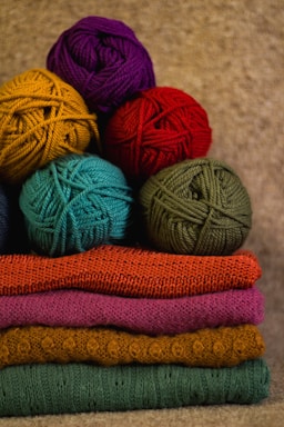 Cozy wool yarn balls and knitted sweaters arranged on a wooden table.