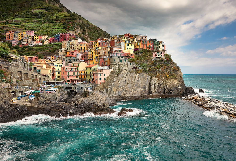 case sulla montagna verde accanto al mare sotto il cielo nuvoloso durante il giorno