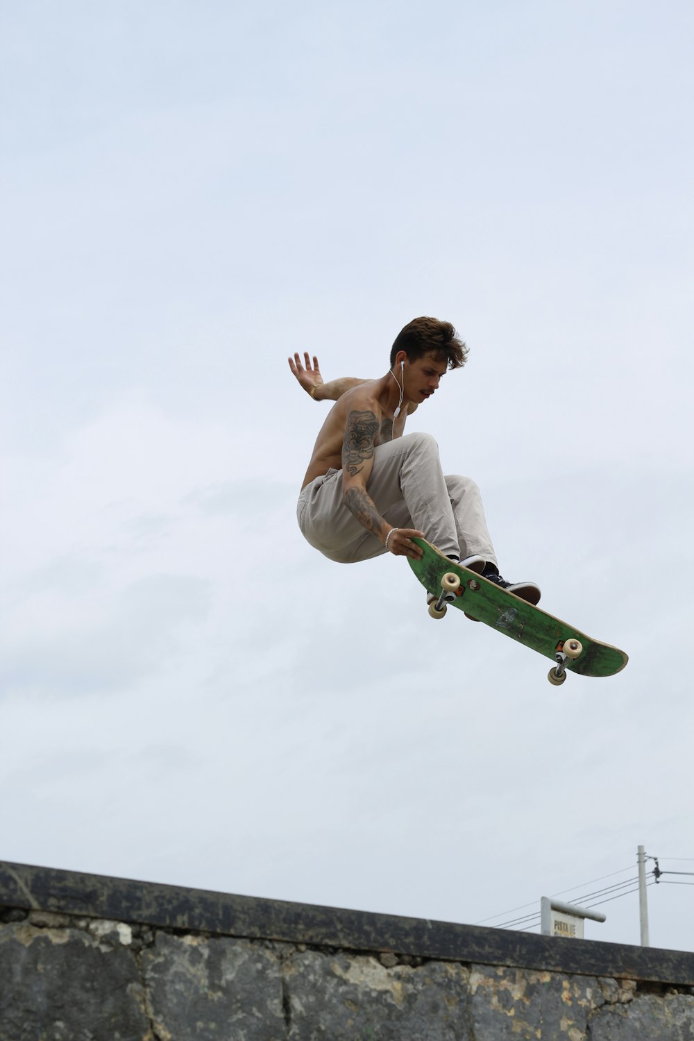 man in white tank top and green pants riding green skateboard during daytime