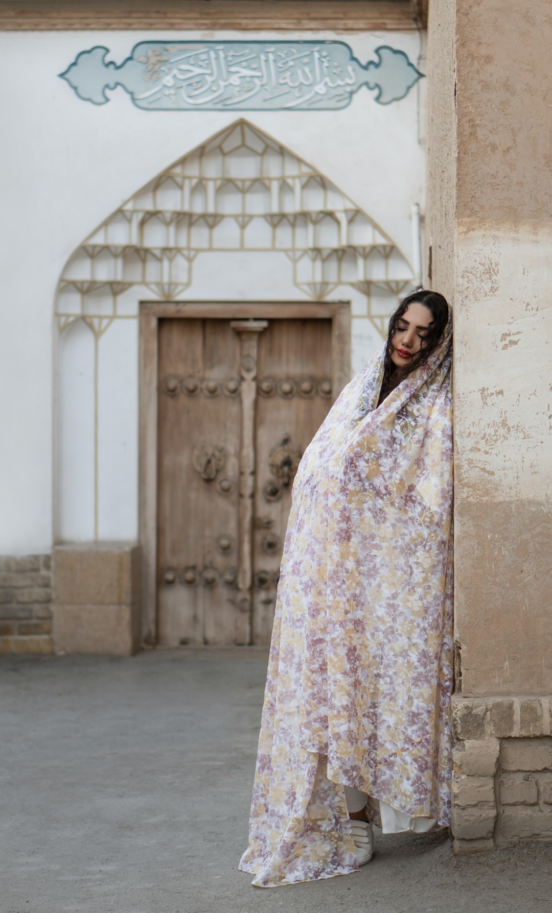 woman in white and pink floral hijab standing near gray concrete wall during daytime