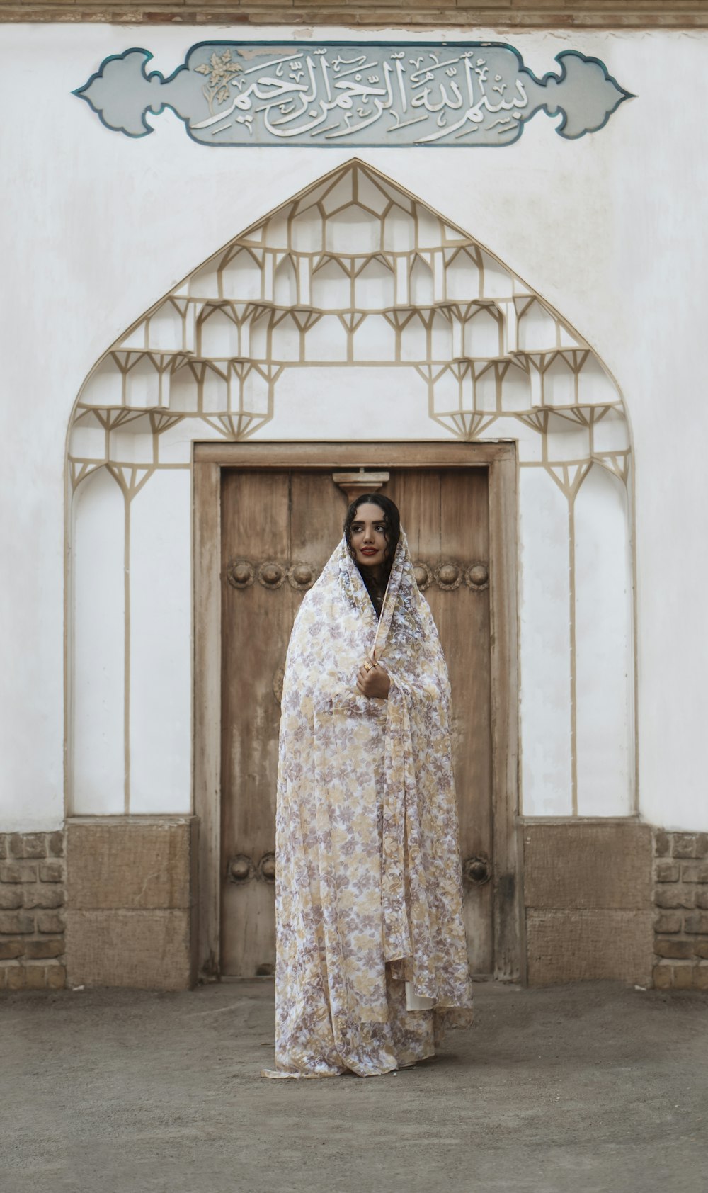 woman in white and blue floral dress standing in front of white concrete wall