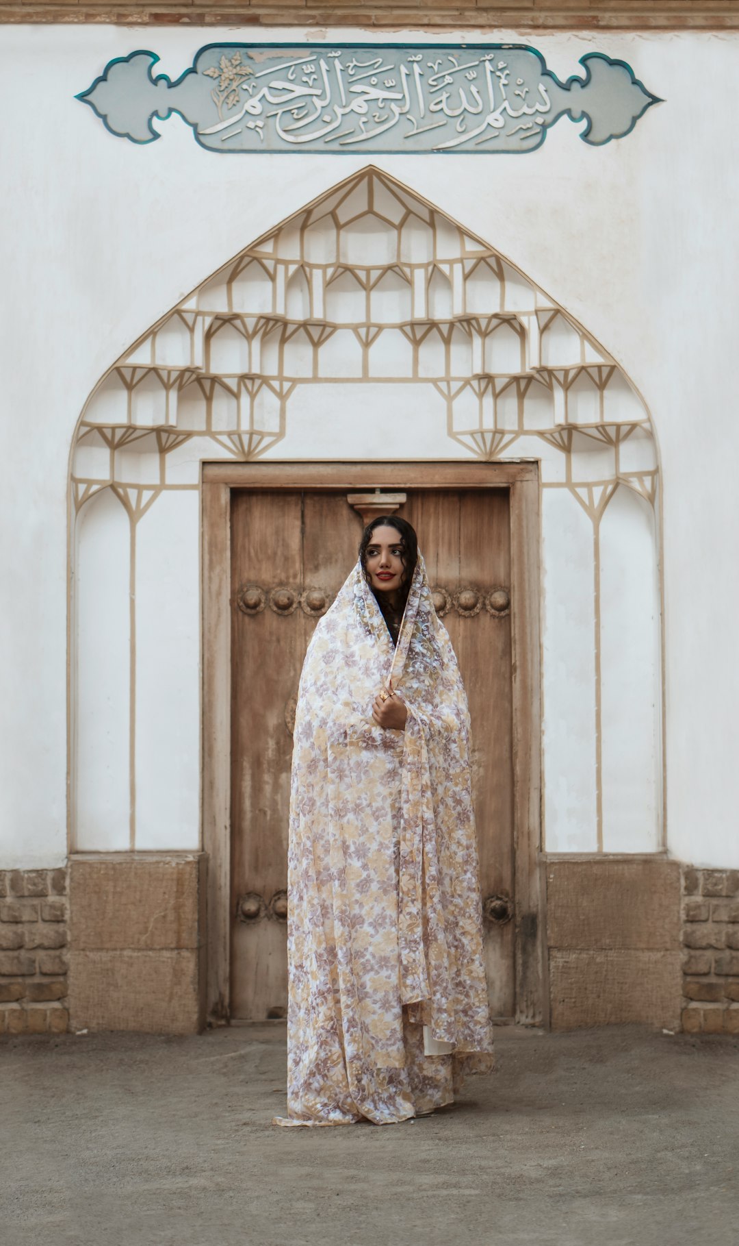 woman in white and blue floral dress standing in front of white concrete wall