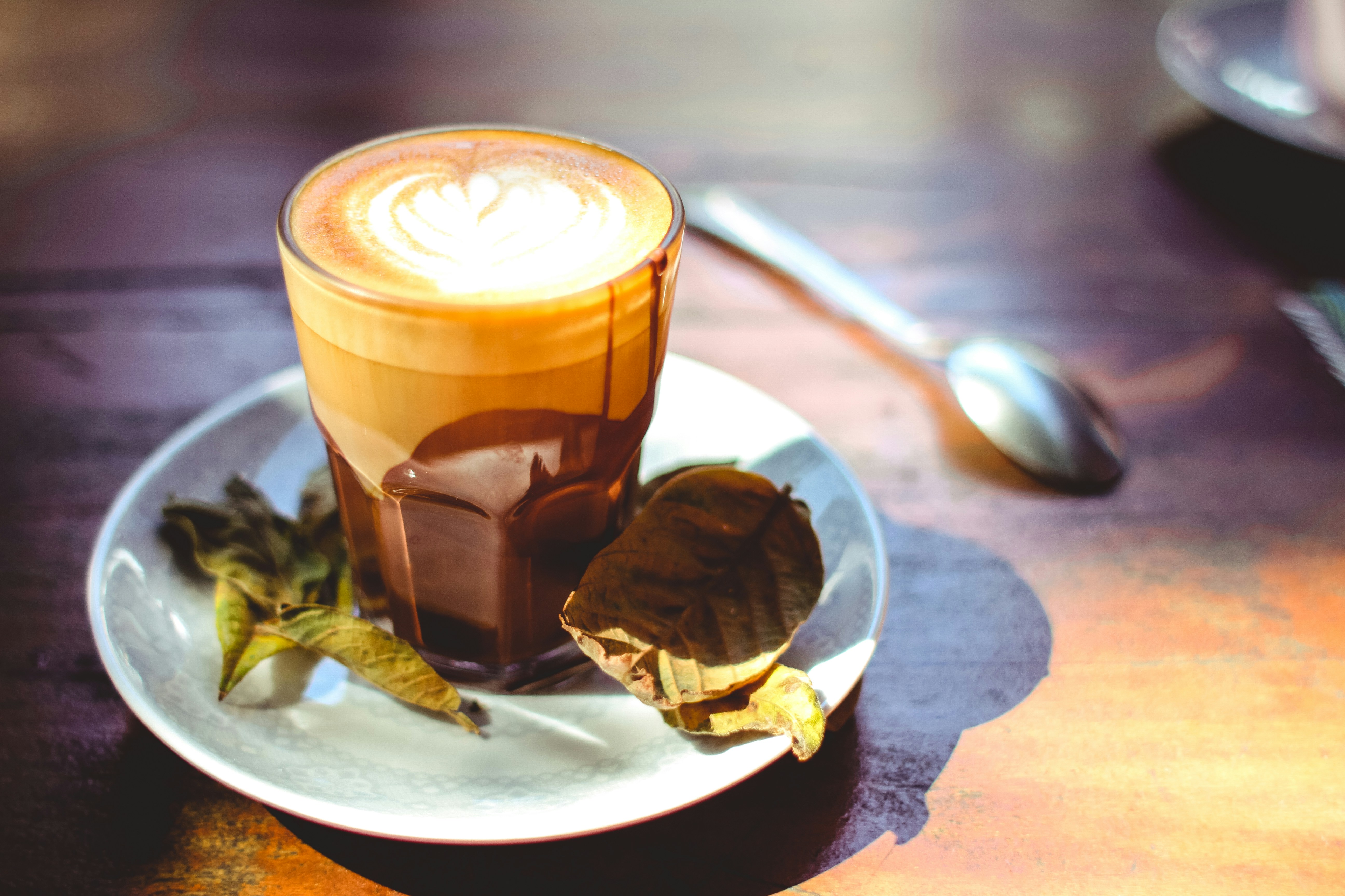 Vaso transparente con líquido marrón sobre platillo de cerámica blanca