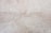 A close-up view of a light beige marble surface with natural veins and patterns, displaying subtle variations in tone and texture.