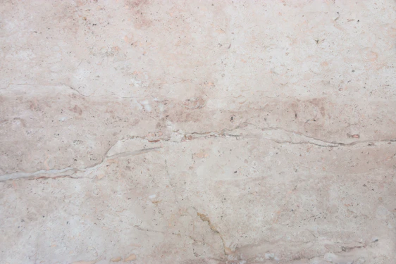 Close-up of a polished white marble slab with subtle beige veins, softly lit to highlight its natural texture and elegance.