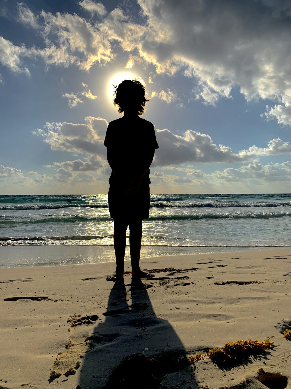 silhouette of woman standing on beach during sunset