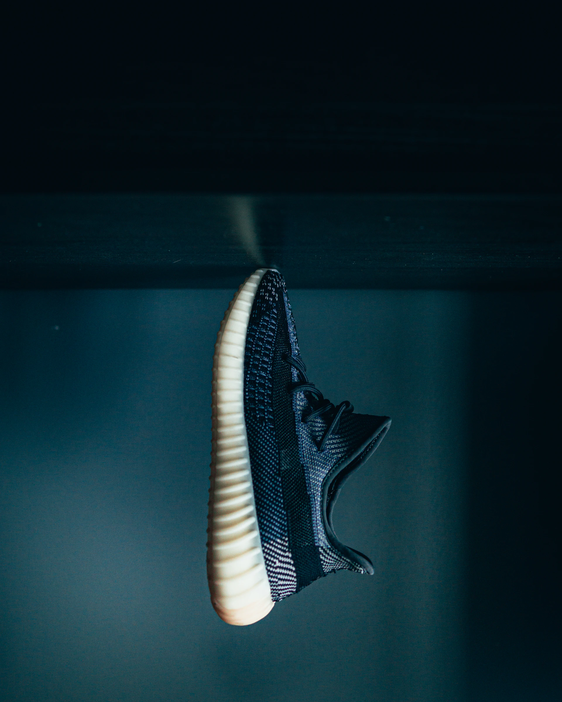 A sleek black background featuring a close-up of a luxury Nike sneaker with sharp white accents, highlighting its premium craftsmanship.