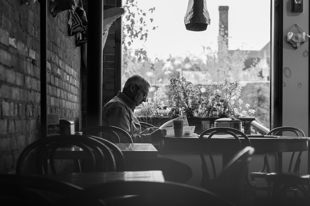 grayscale photo of man sitting on chair