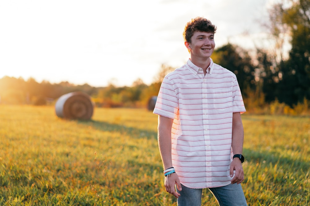 man in white and black stripe polo shirt standing on green grass field during daytime