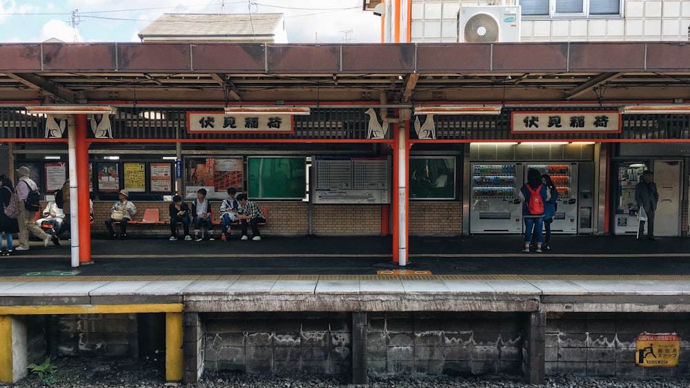 昼間、紅白電車のそばのベンチに座る人々