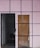 A gated entrance next to a wooden door, both set against a light-colored wall with a grid pattern. The gate is painted black with a padlock securing it, while the wooden door has some graffiti in blue. The wall features a pink hue with purple lines dividing it into squares.